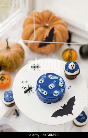 Kürbisse mit Kuchen und Halloween-Dekoration auf dem Tisch zu Hause Stockfoto