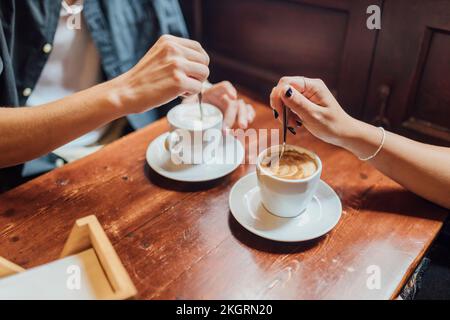 Hände eines jungen Paares, das Kaffee im Café rührt Stockfoto