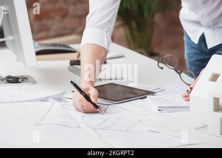 Hand des Architekten, die auf Papier mit Stift am Schreibtisch im Büro schreibt Stockfoto