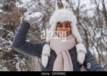 Glücklicher junger Mann, der mit Schneeball spielt Stockfoto