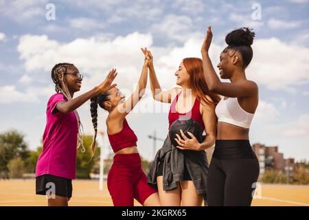 Fröhliche Multirassenfreunde, die High Five auf dem Sportplatz machen Stockfoto