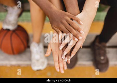 Multirassenfreunde, die sich auf dem Sportplatz die Hände stapeln Stockfoto