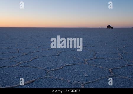 Geländewagen und Personen, die in der Nähe auf der Salar de Uyuni (Uyuni Salzplatte) bei Sonnenaufgang, Potosi Department, Bolivien Stockfoto