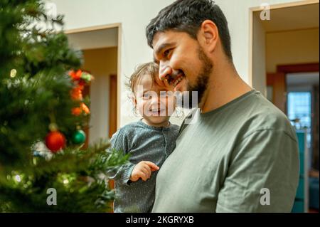 Lächelnder Vater mit Sohn, der den Weihnachtsbaum ansieht Stockfoto