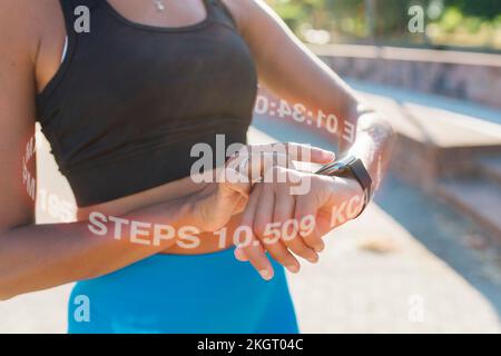 Eine Frau, die den Puls mit einer Smartwatch auf dem Fußweg überprüft Stockfoto