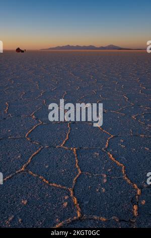 Geländewagen und Personen, die in der Nähe auf der Salar de Uyuni (Uyuni Salzplatte) bei Sonnenaufgang, Potosi Department, Bolivien Stockfoto