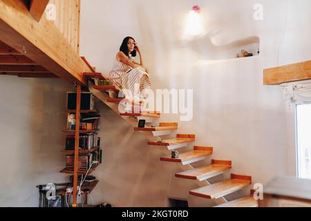 Reife Frau, die zu Hause auf der Treppe sitzt Stockfoto