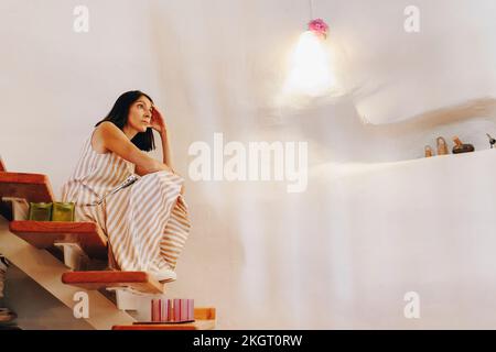 Rücksichtsvolle, reife Frau, die zu Hause auf Stufen sitzt Stockfoto