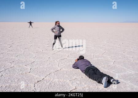 Touristen, die lustige Bilder auf dem Salar de Uyuni (Uyuni Salzwand), Potosi Department, Bolivien machen Stockfoto