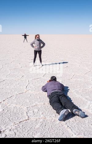 Touristen, die lustige Bilder auf dem Salar de Uyuni (Uyuni Salzwand), Potosi Department, Bolivien machen Stockfoto