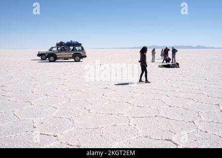 Touristen, die lustige Bilder auf dem Salar de Uyuni (Uyuni Salzwand), Potosi Department, Bolivien machen Stockfoto