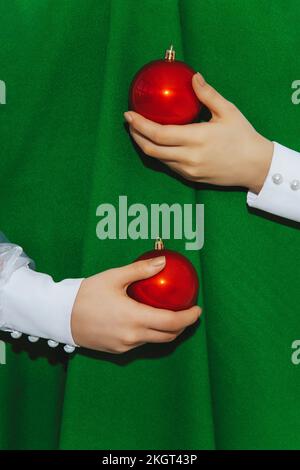 Die Hände eines Mädchens mit Kugeln, die den abstrakten Weihnachtsbaum umschließen Stockfoto