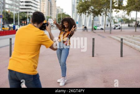 Ein junger Mann fotografiert eine Frau durch die Kamera auf dem Fußweg Stockfoto