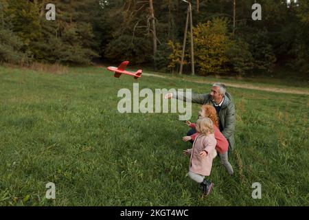 Großvater und Enkel, die auf dem Rasen mit Flugzeugspielzeug spielen Stockfoto