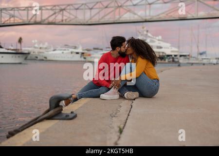 Romantisches junges Paar, das sich bei Sonnenuntergang auf der Promenade küsst Stockfoto