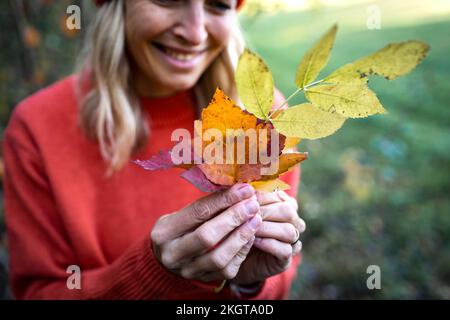 Reife Frau mit Herbstblättern Stockfoto