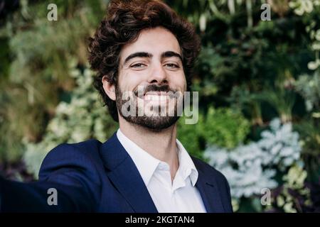 Hübscher, glücklicher Geschäftsmann mit Pflanzen im Hintergrund Stockfoto