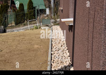 Ein Abflussweg aus dekorativen Steinen um die Wand des Hauses Stockfoto