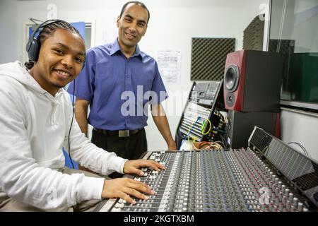 Musikschüler: Audiotechniker. Ein junger Toningenieur, der mit seinem Lehrer die Verwendung eines Mixpults in einem Musikstudio lernt. Aus einer Reihe von zugehörigen Bildern. Stockfoto