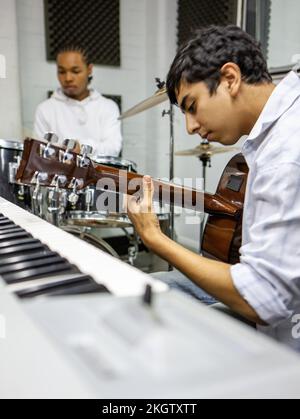 Musikschüler: Gitarre Solo. Eine Jamming-Session zwischen einem Gitarrist und einem Schlagzeuger in einem Musikstudio. Aus einer Reihe von zugehörigen Bildern. Stockfoto