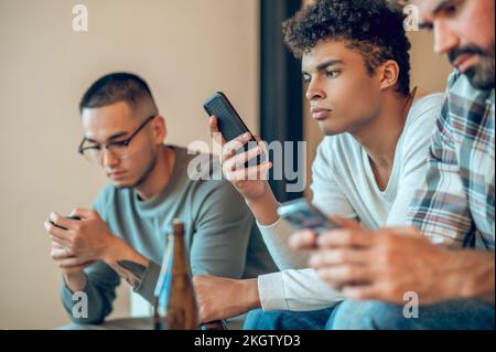 Gesellschaft gelangweilter Freunde, die sich die Zeit mit ihren Smartphones vertreiben Stockfoto