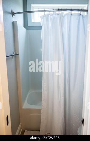 Kleines Bad mit Badewannen-Duscheinsatz und weißem Duschvorhang Stockfoto