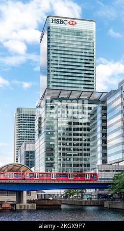 Canary Wharf der blaue Himmel von HSBC spiegelt sich am North Dock mit dem HSBC-Gebäude und dem Bahnhof West India Quay wider. Der U-Bahn-Zug London E14 Stockfoto