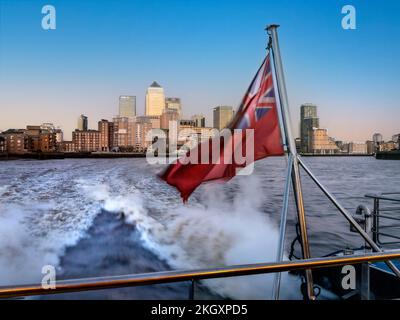 CANARY WHARF Thames Clipper River Boot RB1 verschwommen bei Geschwindigkeit, mit traditioneller roter Fahne von Canary Wharf bei Sonnenuntergang auf der Themse London UK Stockfoto