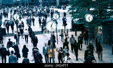 PENDLER DRÄNGEN TIME CANARY WHARF UHREN LONDON 18,05 Pendler Canary Wharf Cross Rail South Colonnade mit Schweizer weißer Ziffernuhr, die genaue Fahrtzeiten anzeigt. Büromitarbeiter, die am Ende des Arbeitstages täglich nach Hause pendeln, Canary Wharf London UK Stockfoto