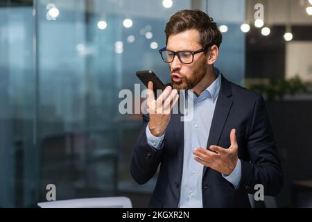 Senior-Boss, wütend, schreiend, telefonisch, Geschäftsmann im Business-Anzug, im Büro nahe dem Fenster. Stockfoto