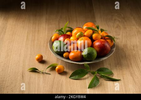 Ein großer Teller mit saftigen Zitrusfrüchten auf einem Holztisch Stockfoto