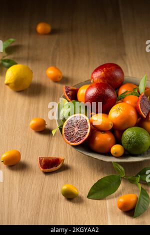 Ein großer Teller mit saftigen Zitrusfrüchten auf einem Holztisch Stockfoto
