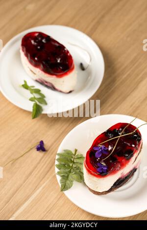 Ein unglaublich cremiges Dessert mit Beerengelee und violetten Blumen auf einem weißen Teller Stockfoto