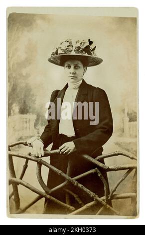 Originelles, leicht polarisiertes Studioporträt aus der edwardianischen Ära mit attraktiver junger Frau, die einen aufwändigen großen Hut trägt, im „Garten“-Stil, ca. 1908. Stockfoto