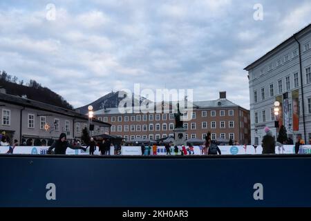 Salzburg, Österreich - 30. November 2019: Eislaufen auf einer Eislaufbahn in der Altstadt von Salzburg, Österreich, mit einem Berg im Gebirge im kalten Herbst Stockfoto