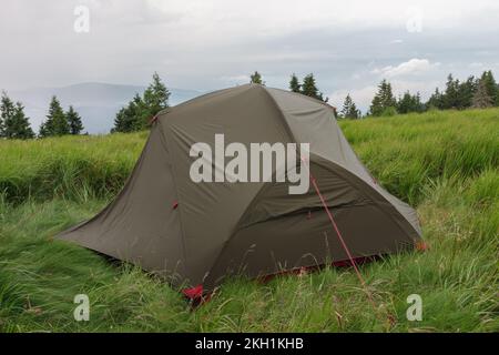 Grünes, leichtes, freistehendes Zelt für 2 Personen auf dem Mravenecnik-Hügel im Gras am Morgen nach dem Regensturm. Jesenik-Gebirge, tschechisch Stockfoto