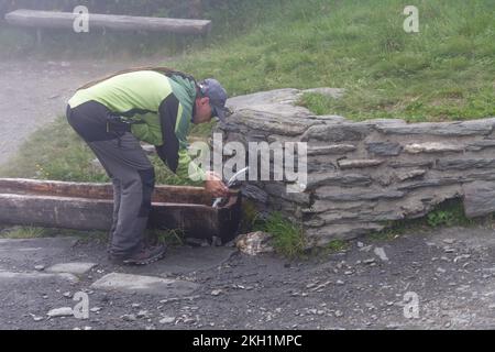 Ein Mann, der Wasser aus einer herzhaften Quelle im Jesenik-Gebirge trinkt. Sein Name ist Reh Spring. Stockfoto