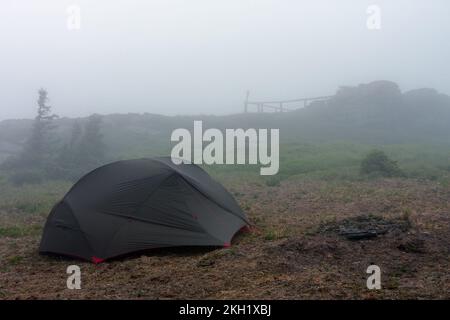 Grünes, leichtes, freistehendes Zelt für 2 Personen auf einem Hügel im Gras am Abend nach dem Regensturm. Jesenik-Berge, Tschechische Republik Stockfoto