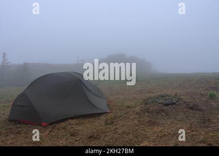 Grünes, leichtes, freistehendes Zelt für 2 Personen auf einem Hügel im Gras am Morgen nach dem Regensturm. Jesenik-Berge, Tschechische Republik Stockfoto