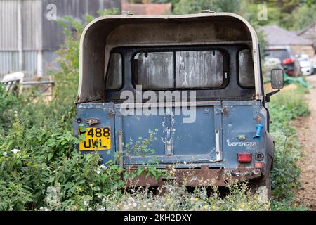 Der alte Land Rover ist am Rande eines Bauernhofes zwischen Zwiebeln und Unkraut abgehauen. UK. Stockfoto