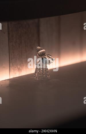 Ein vertikaler Schuss einer Engelsfigur aus Glas mit einem gebrochenen Flügel Stockfoto