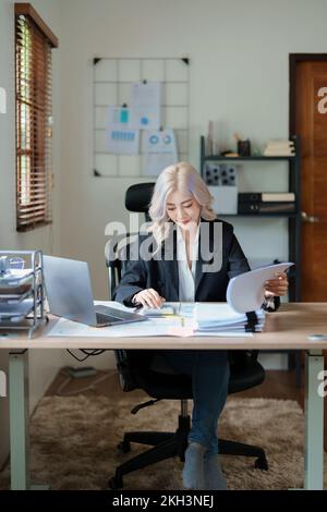 Buchhalter, asiatische Wirtschaftsprüfer verwenden Rechner und Computer, um die jährlichen Steuerbudgets zu überprüfen, um Informationen an das IRS zu übermitteln. Stockfoto