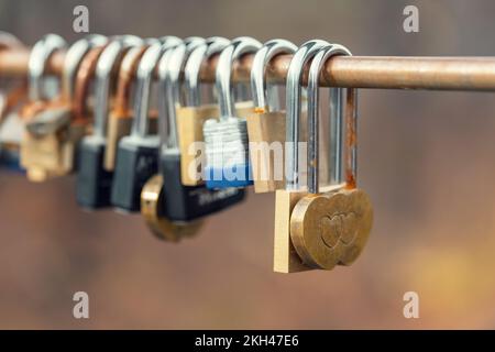 Herzförmige Liebesschlösser, die im Herbst an der Brücke hängen. Konzept von Liebe, Freundschaft und Zuneigung. Stockfoto