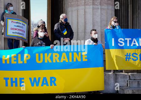 Die Menschen halten während einer Demonstration gegen den Russischen Krieg in der Ukraine große Banner in den ukrainischen Nationalfarben mit Inschriften Help Ukraine. Stockfoto