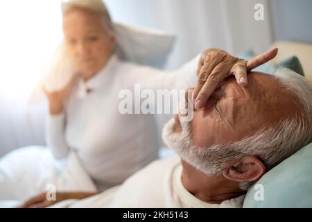 Gestresste Seniorin hat Probleme im Schlafzimmer, weil ihr Mann schnarcht. Seniorenpaar hat Probleme mit Männerschnarchen. Stockfoto