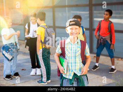 Lächelnder Grundschuljunge, der im Freien steht Stockfoto