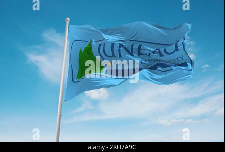 Offizielle Flagge von Juneau, Alaska Unbanden Staaten von Amerika bei bewölktem Himmel Hintergrund bei Sonnenuntergang, Panoramablick. USA Reisen und patriotische Konzept. Kopieren Sie den SPAC Stockfoto