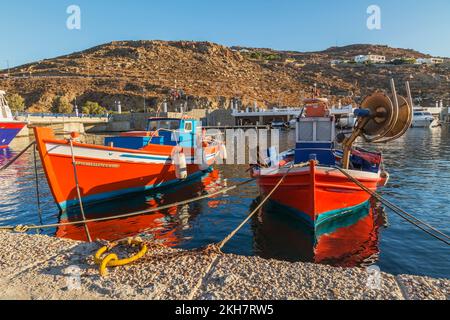 Kleine traditionelle orange, weiße und blaue griechische Fischerboote mit Bootsfänger, die bei Sonnenaufgang im neuen Hafen von Mykonos auf der Insel Mykonos, Griechenland, angedockt sind. Stockfoto