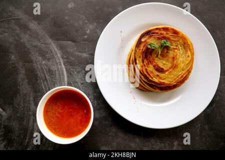 Paratha-Brot oder Canai-Brot oder Rotwein maryam, Lieblingsfrühstück. Serviert auf dem Teller Stockfoto