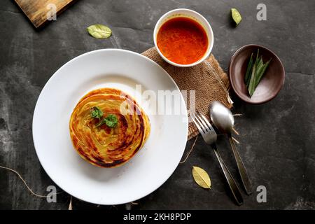 Paratha-Brot oder Canai-Brot oder Rotwein maryam, Lieblingsfrühstück. Serviert auf dem Teller Stockfoto